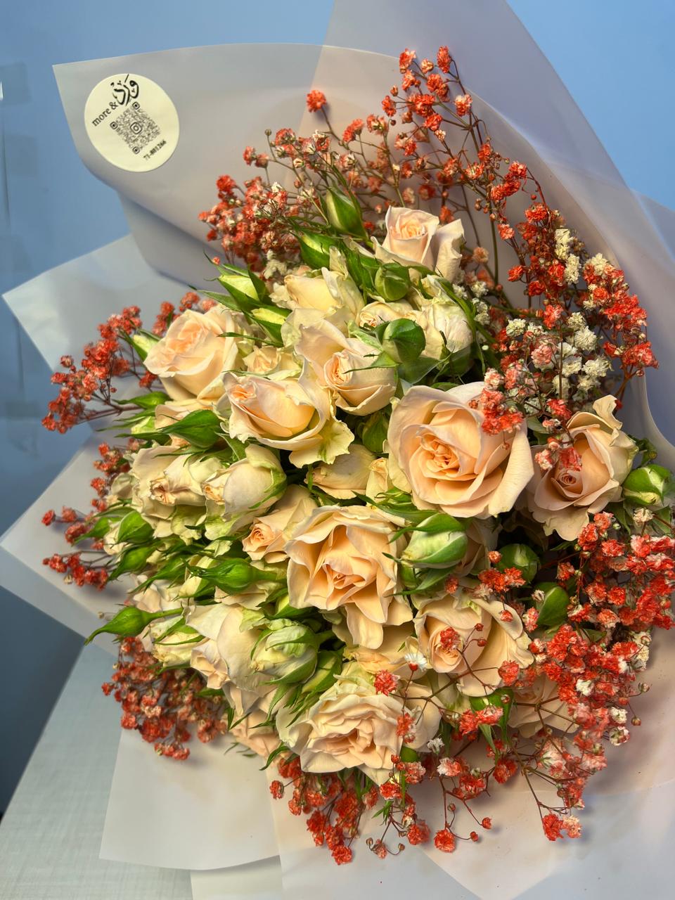 Peach roses with coral baby's breath in soft blue paper